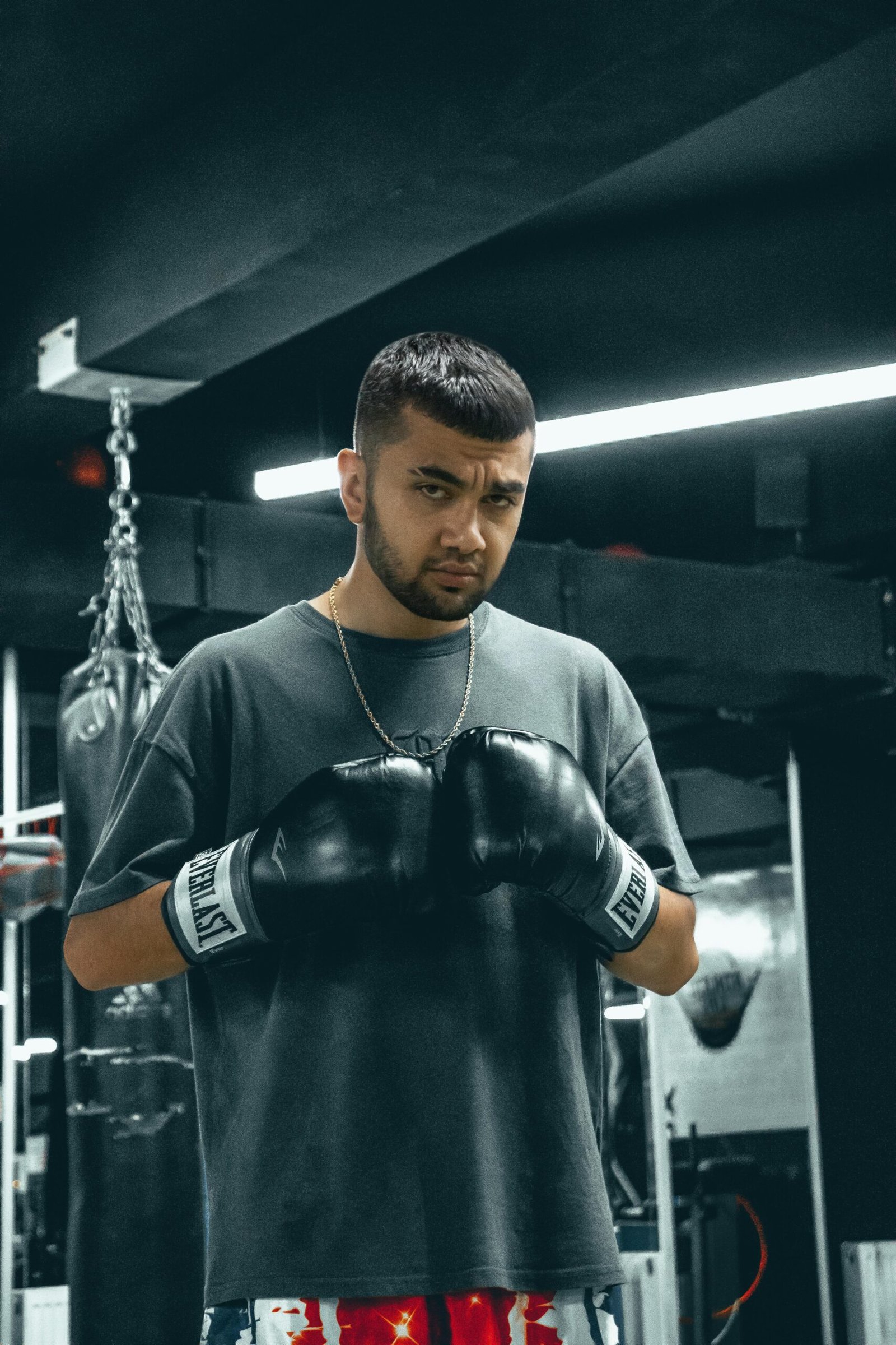Focused young man wearing boxing gloves in a gym setting, preparing for a session.