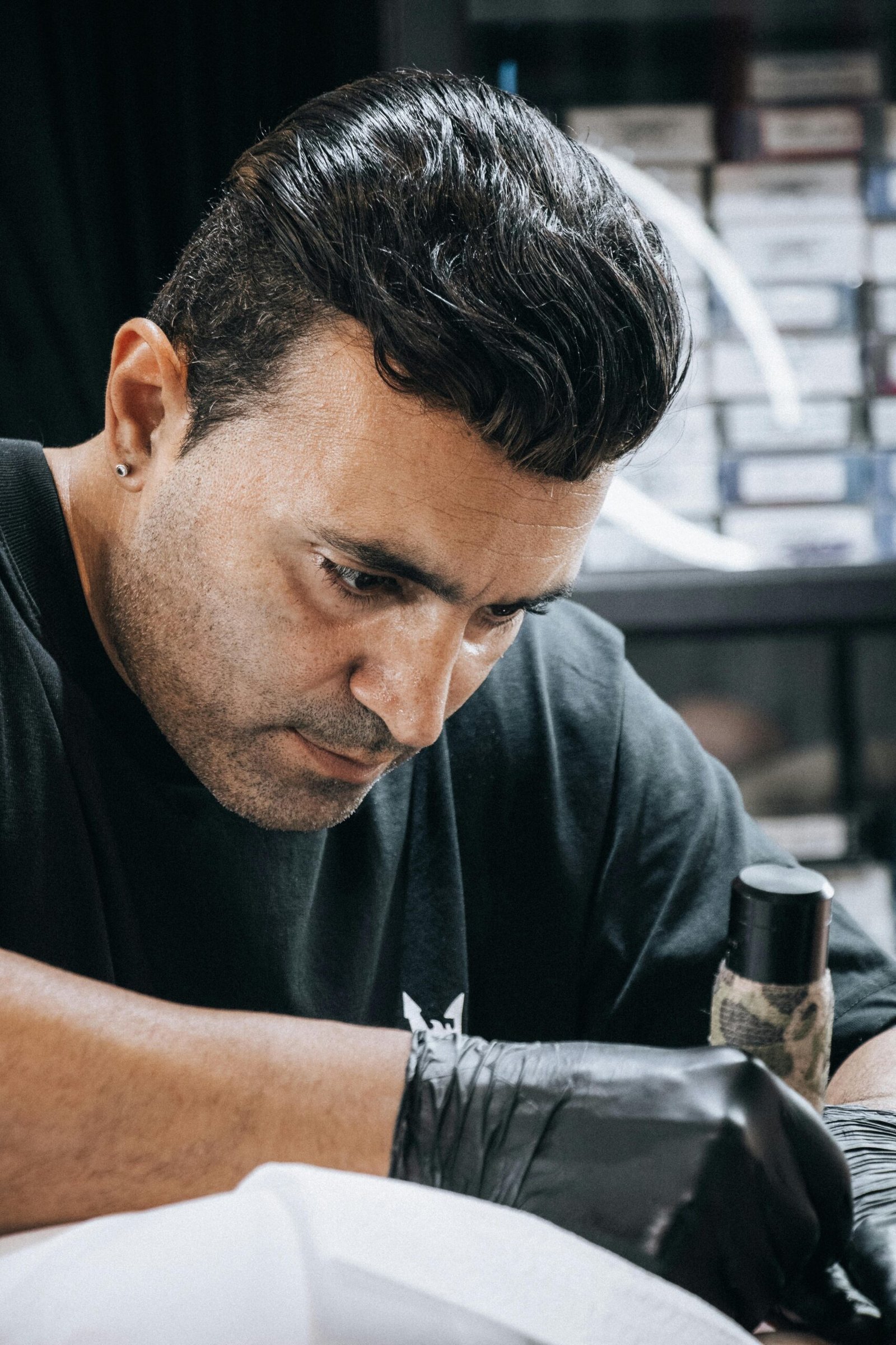 A tattoo artist intently works on a design in a professional studio setting.